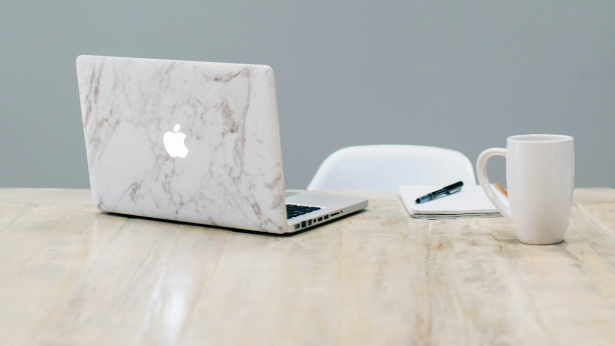 MacBook on table near mug