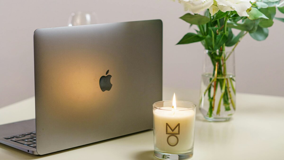 a vase of flowers and a laptop on a table