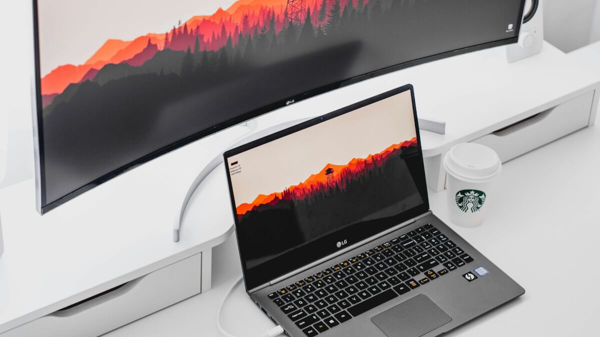 laptop computer beside curved monitor