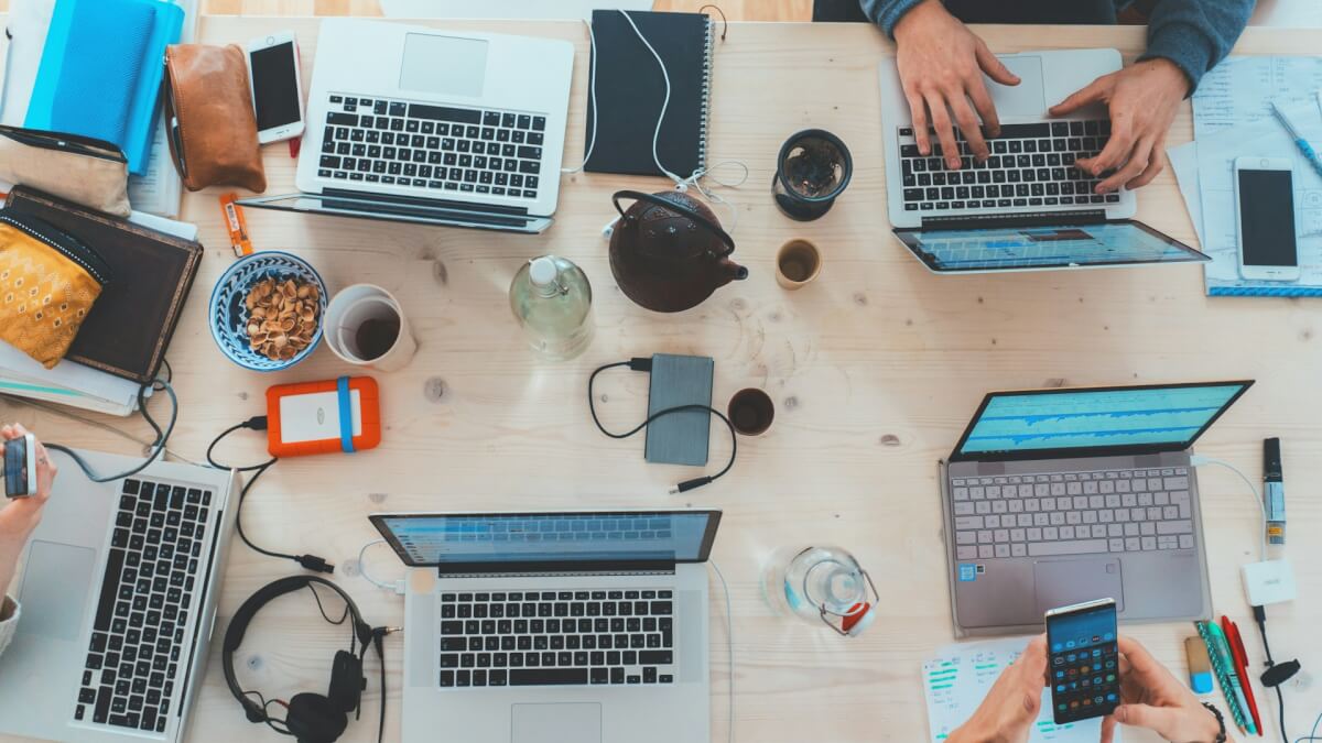 people sitting down near table with assorted laptop computers