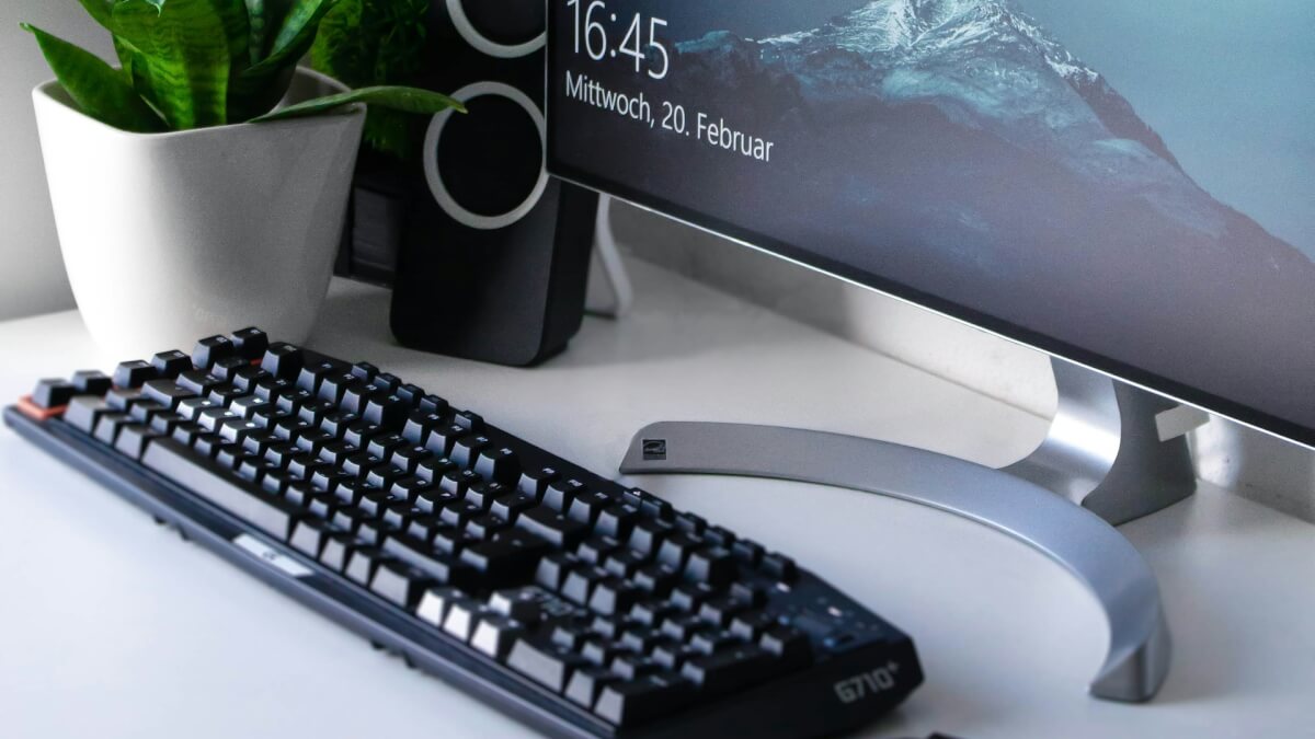 black Logitech G710+ wireless keyboard and wireless mouse near gray flat screen computer monitor on table