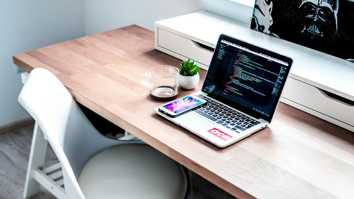 smartphone on laptop computer on top of brown wooden desk