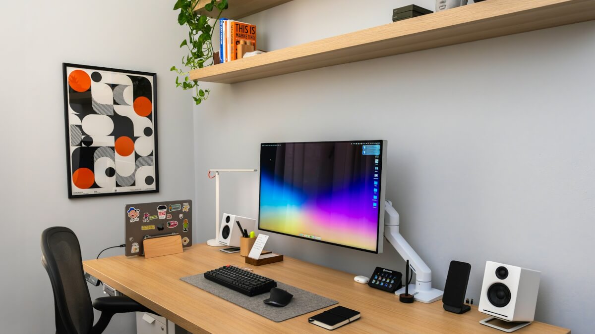 a desk with a computer monitor, keyboard and speakers