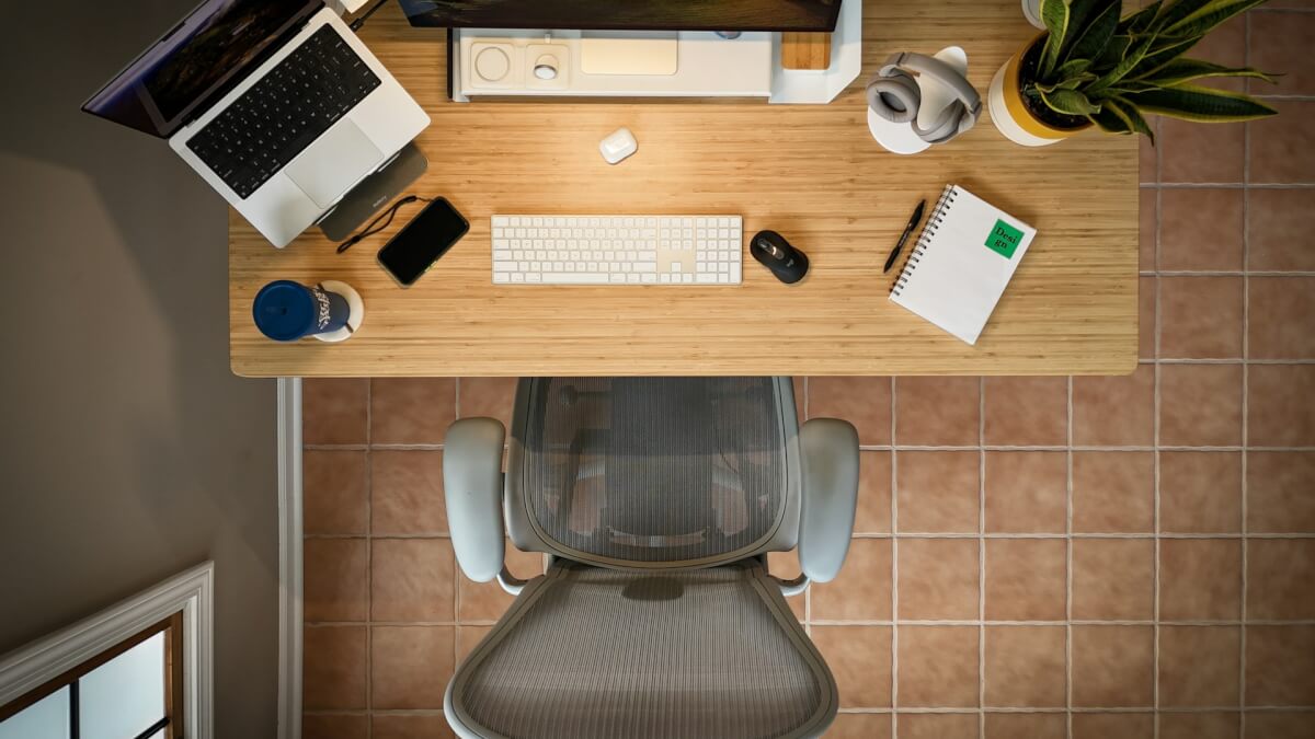 an overhead view of a desk with a laptop, keyboard, mouse, and a