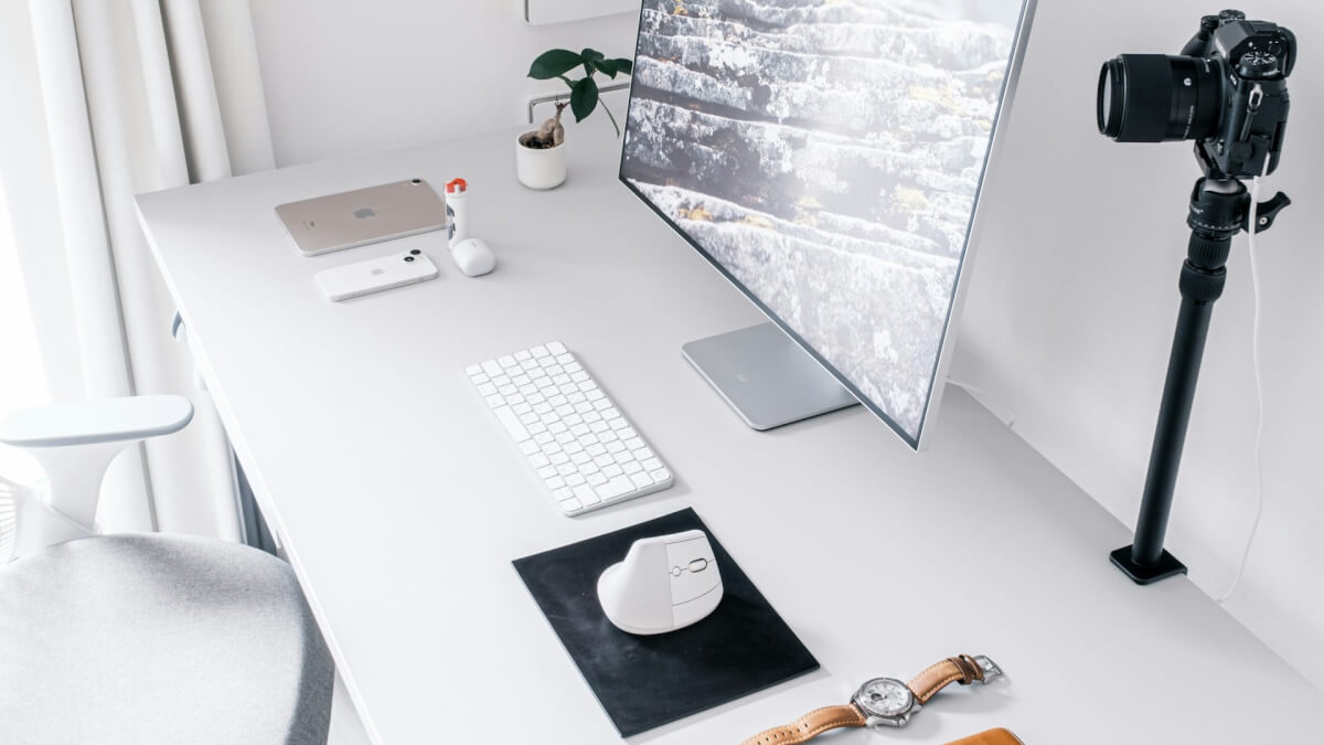 a desk with a monitor, keyboard, mouse and a camera