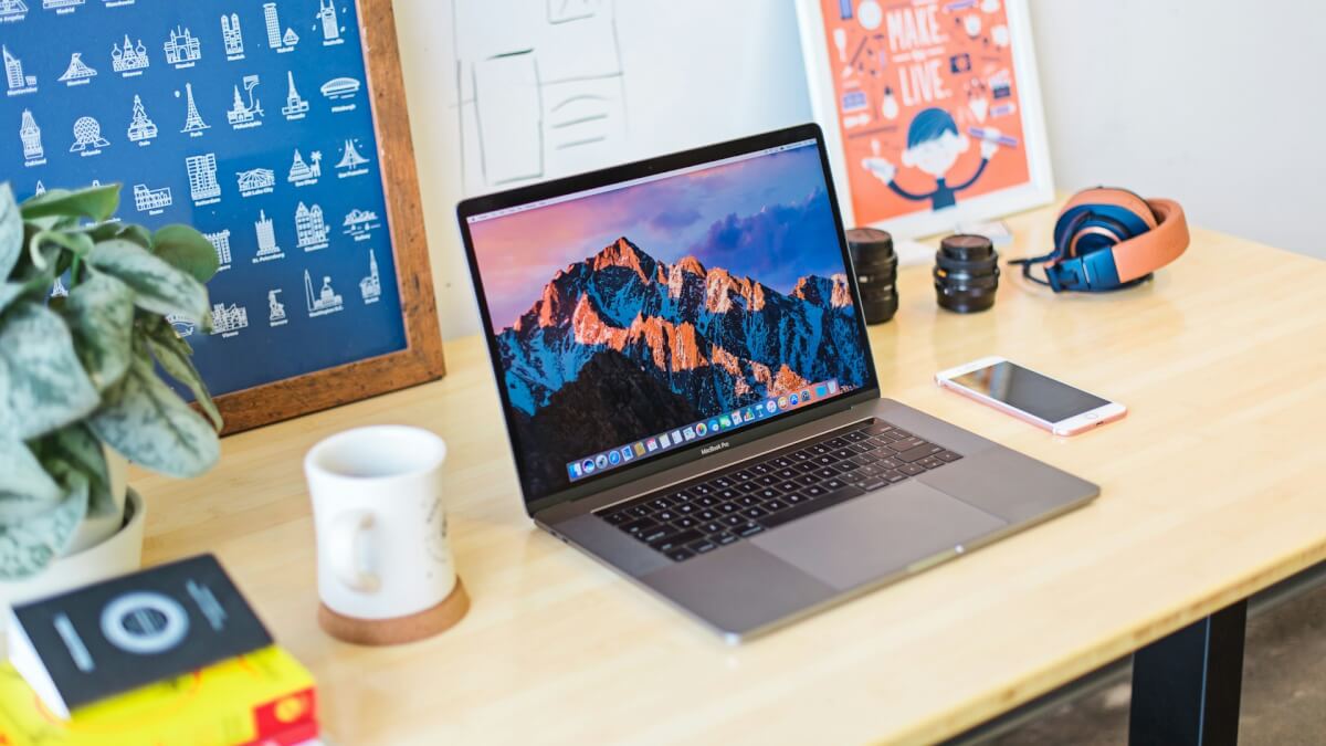 turned on MacBook Pro beside white ceramic mug