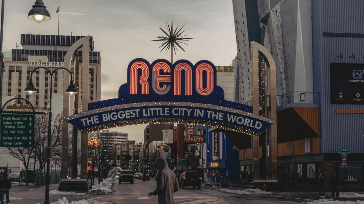 a man walking down a street under a neon sign