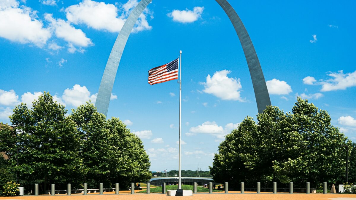 us flag on pole near trees during daytime