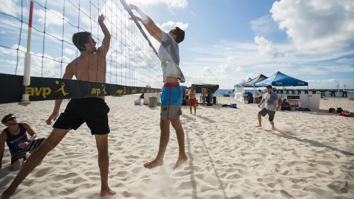 man in white shirt and blue shorts playing volleyball on beach during daytime